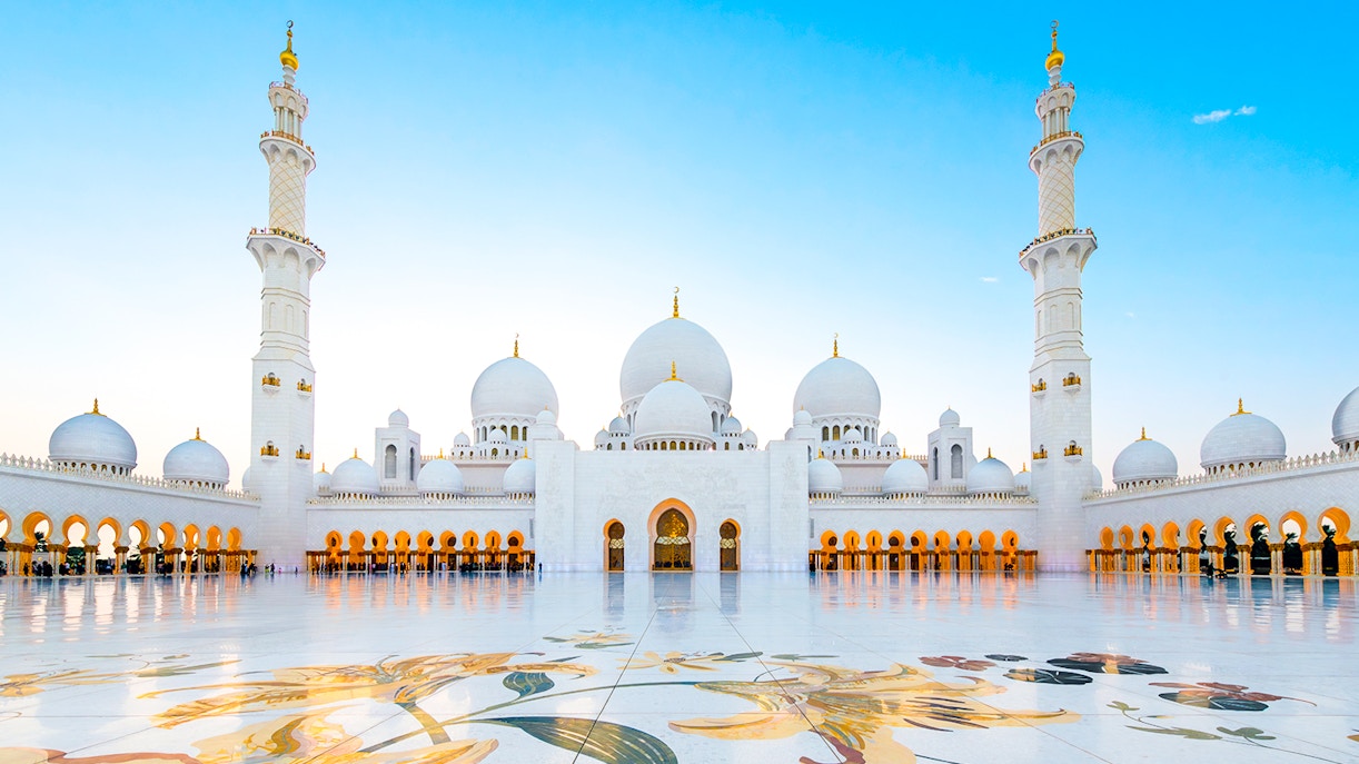 Interior courtyard of Sheikh Zayed Grand Mosque, Abu Dhabi, showcasing intricate white marble columns and arches.