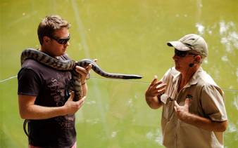 Man holding a snake during a wildlife demonstration at Hartley's Crocodile Adventures.