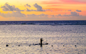 Tourist kayaking at sunset on Flic en Flac beach, Mauritius Island, Africa.