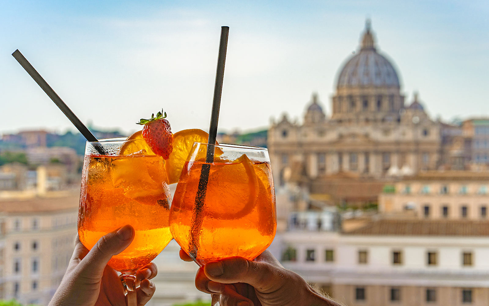 Tourist holding prosecco spritz with St Peter's Basilica in the background, Rome.