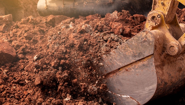 Ein Bagger nimmt mit seiner Schaufel Erde auf