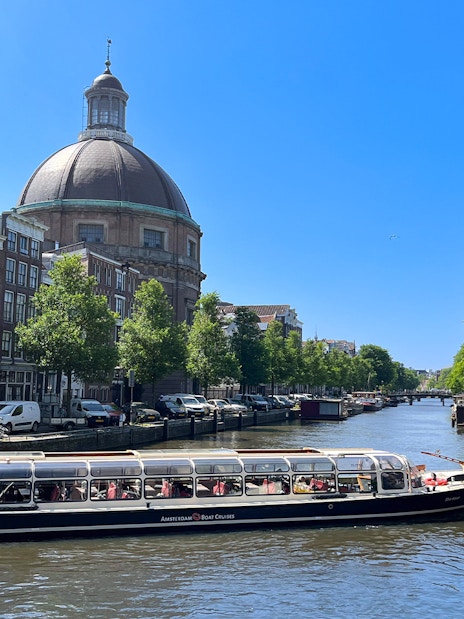 Canal boat cruising past the dome of St. Nicholas Church in Amsterdam.