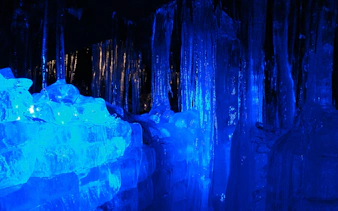 Ice formations inside Fugaku Wind Cave, Japan, illuminated in blue light.