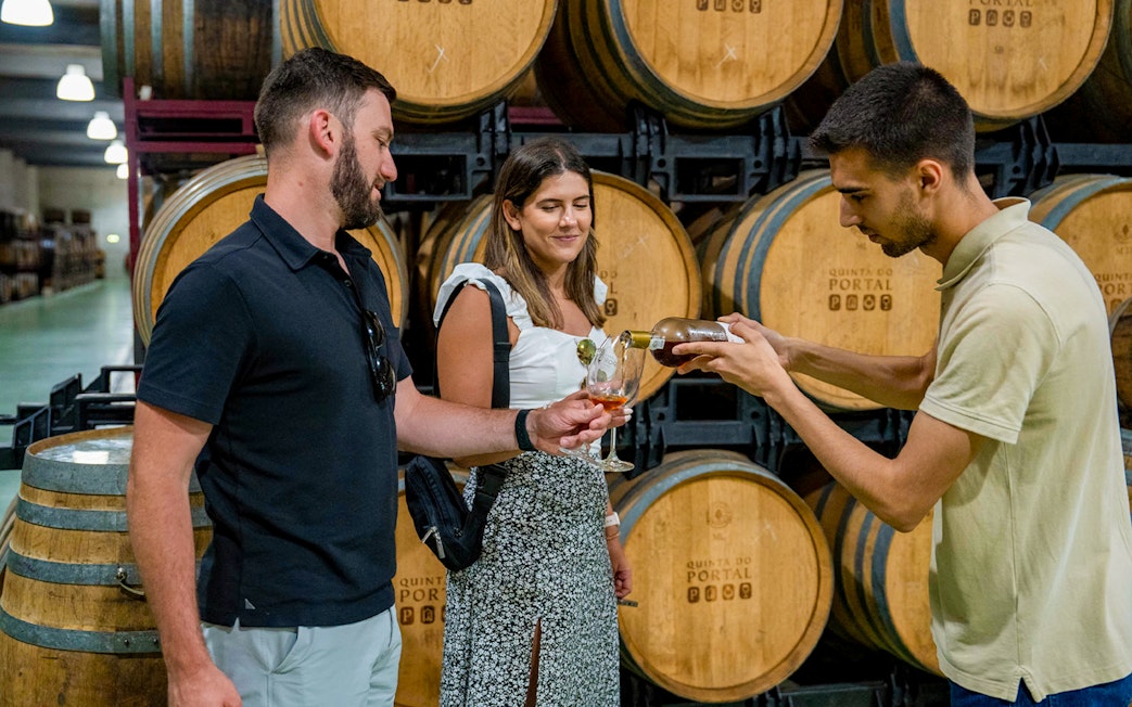 Tourist with guide tasting wine in a cellar with wooden barrels Douro