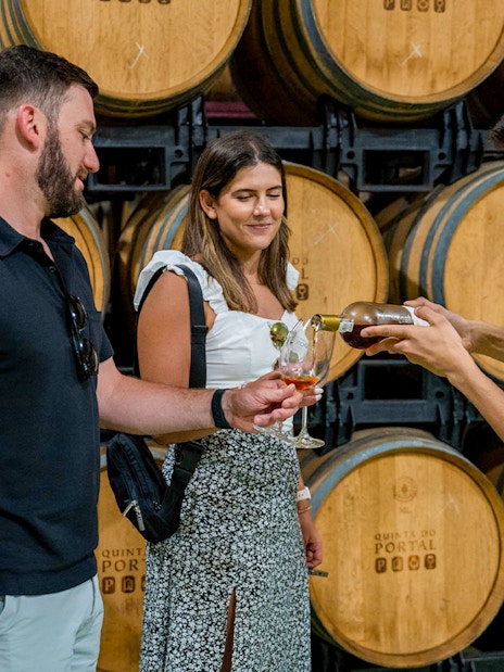 Tourist with guide tasting wine in a cellar with wooden barrels Douro