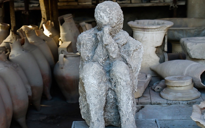 Pompeii plaster cast of a victim with amphorae in the background, Italy.