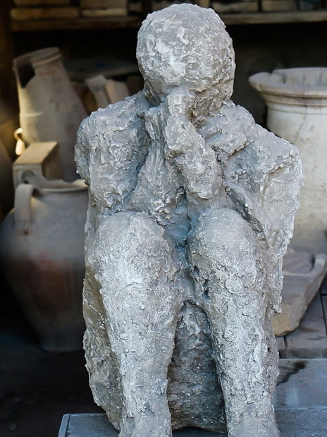 Pompeii plaster cast of a victim with amphorae in the background, Italy.