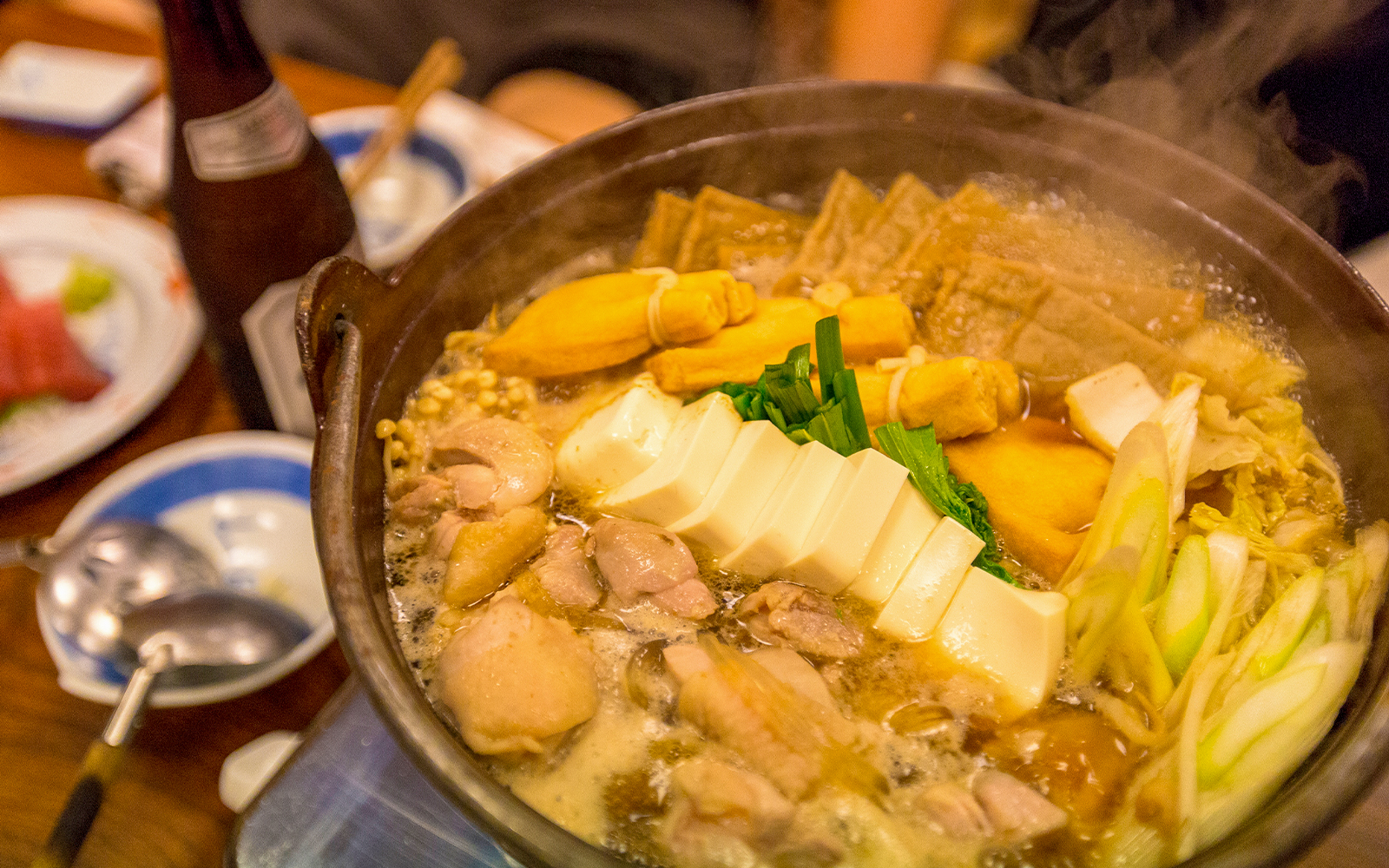 Sumo wrestlers hot pot with tofu, vegetables, and chicken in a steaming broth.