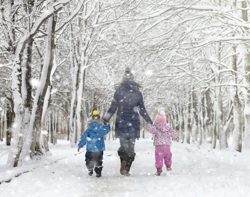 Family walking through snowy Central Park path.