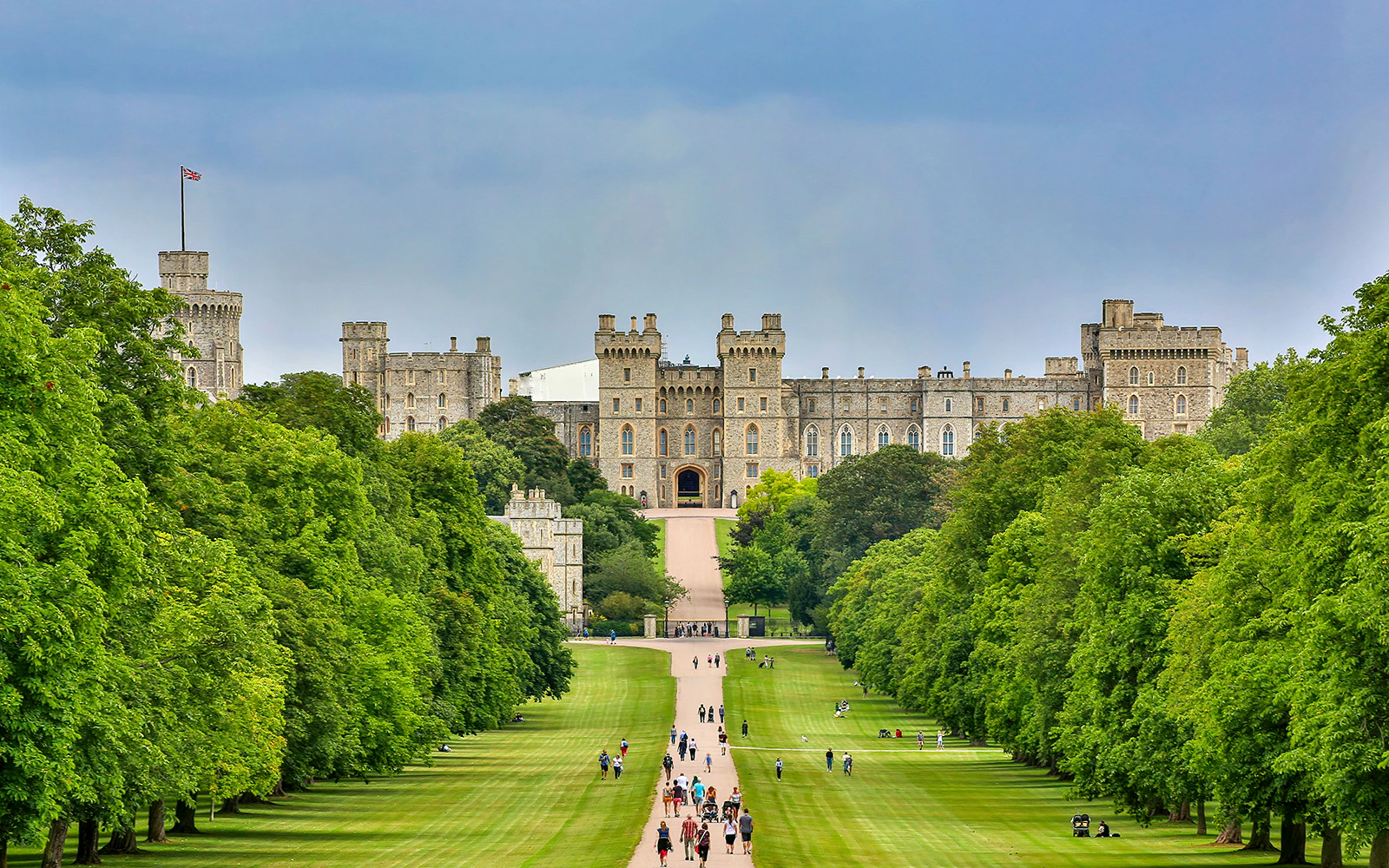 Windsor Castle with visitors walking along the Long Walk path.