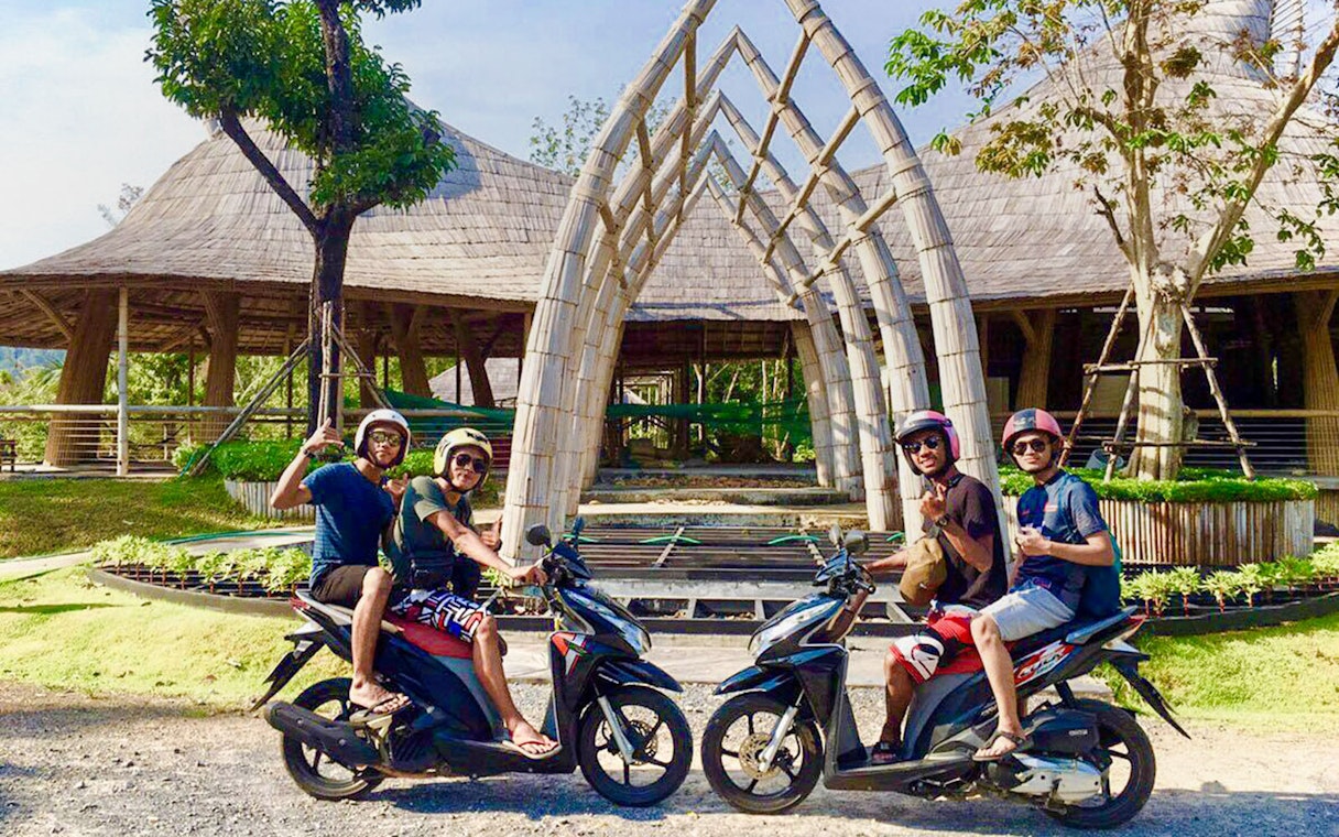 Guests on scooters at Emerald Pools & Hot Spring, Pita village, with bamboo architecture.