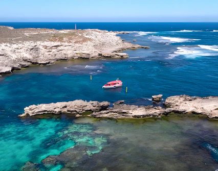 Tourists on a boat tour near Rottnest Island with Perth skyline in the distance.