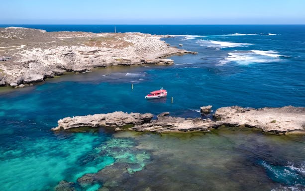 Tourists on a boat tour near Rottnest Island with Perth skyline in the distance.