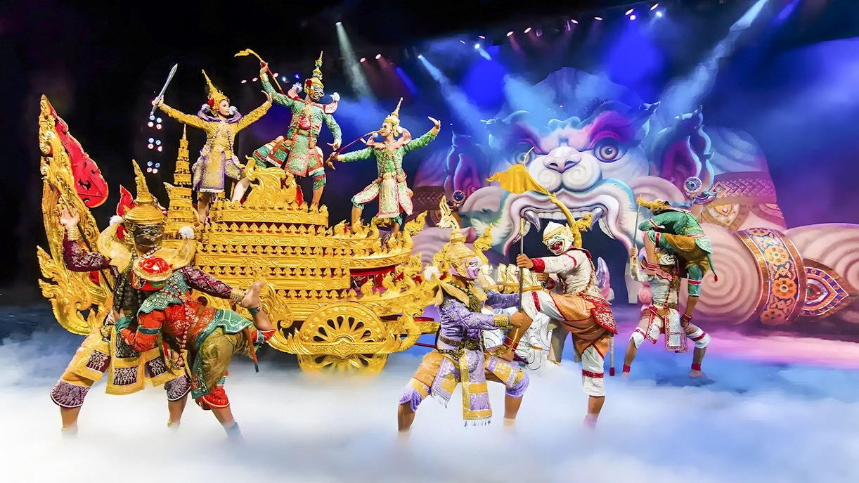 Artistas de Phuket Fantasea con trajes tradicionales tailandeses durante una vibrante escena mítica.