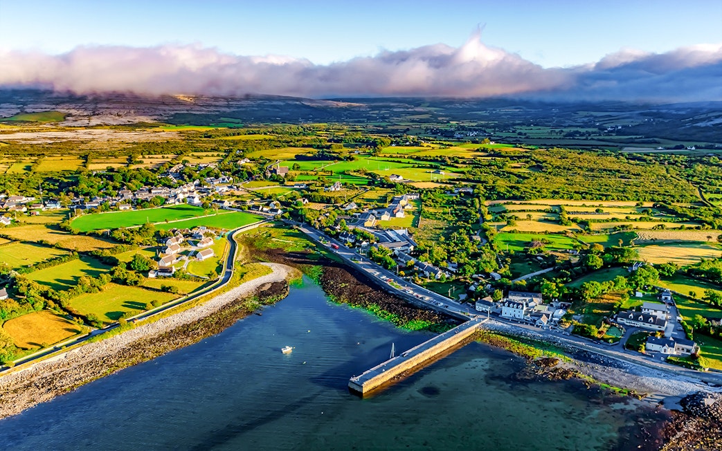 Aerial view of Ballyvaughan village and coastline, featuring lush fields and a small harbor.
