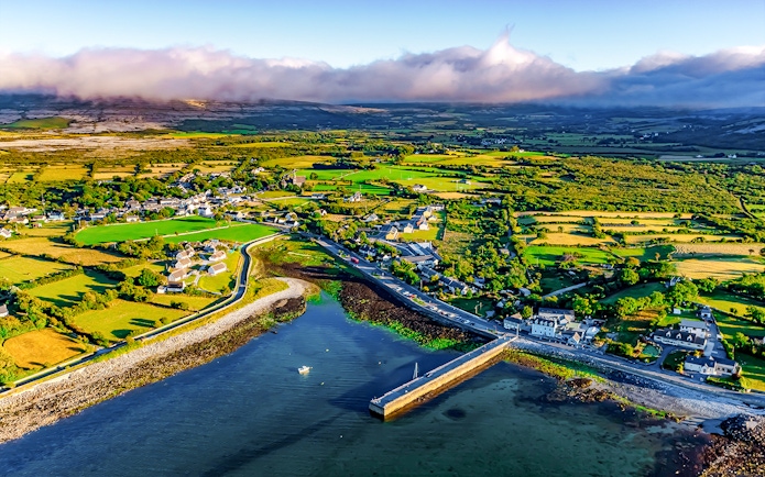 Aerial view of Ballyvaughan village and coastline, featuring lush fields and a small harbor.