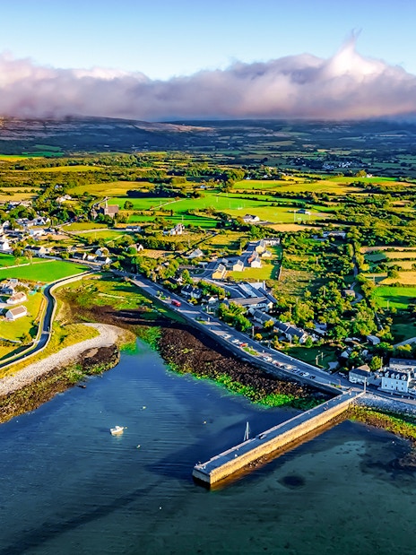 Aerial view of Ballyvaughan village and coastline, featuring lush fields and a small harbor.