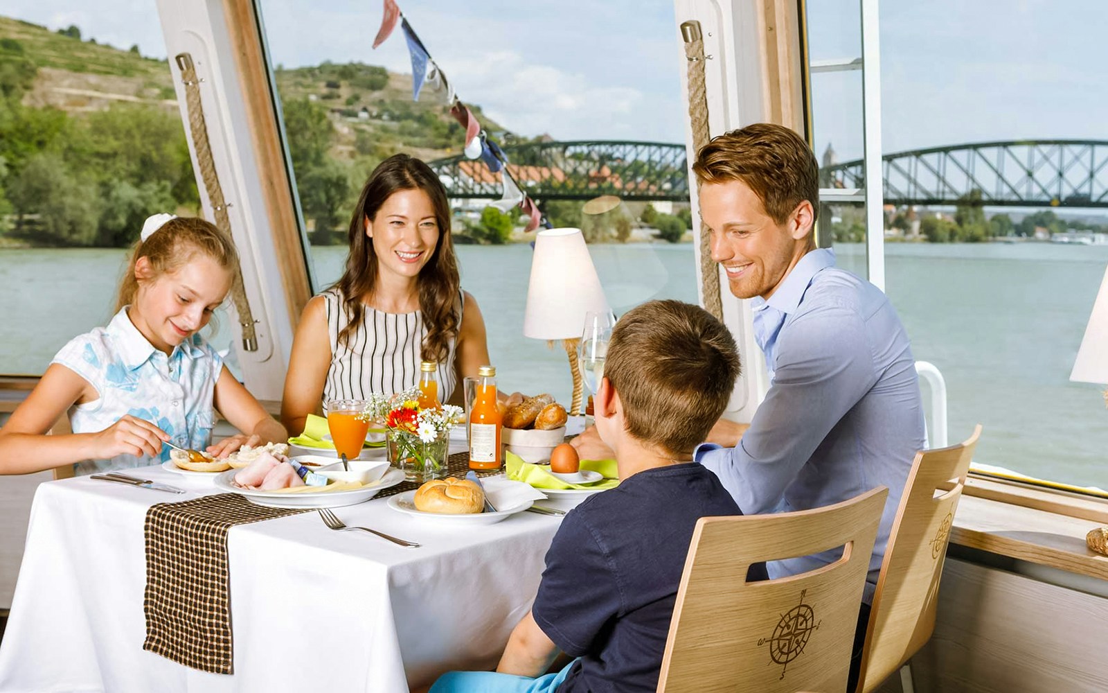 Family dining on Danube river cruise, Vienna with bridge view.