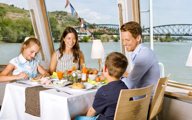 Family dining on Danube river cruise, Vienna with bridge view.