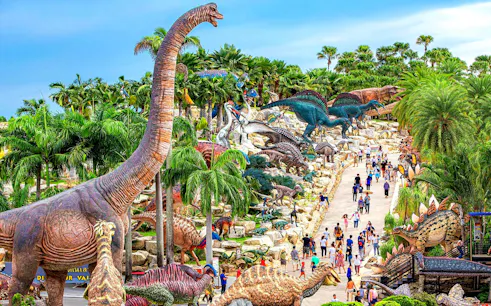 Nong Nooch Tropical Garden dinosaur sculptures and visitors on a pathway in Thailand.