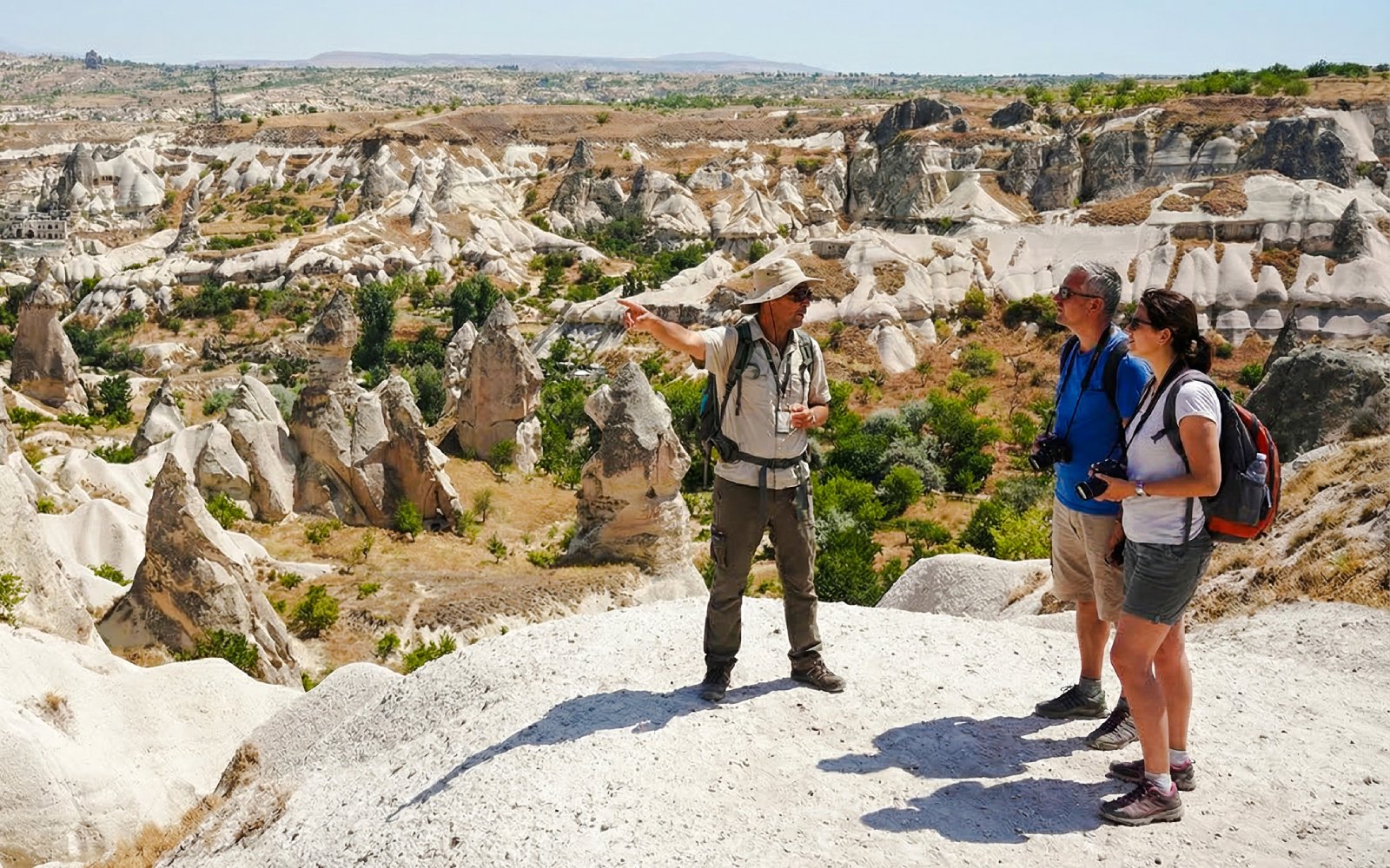 Tour guide pointing out rock formations in Goreme Valley, Cappadocia to tourists.