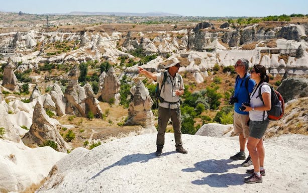 Tour guide pointing out rock formations in Goreme Valley, Cappadocia to tourists.