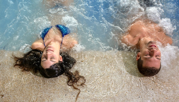 People enjoying the Széchenyi thermal bath in Budapest, Hungary, with historic architecture in the background.