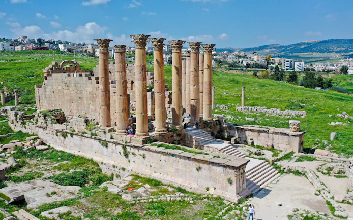 Temple of Artemis ruins in Jerash, Jordan, with ancient columns and surrounding landscape.
