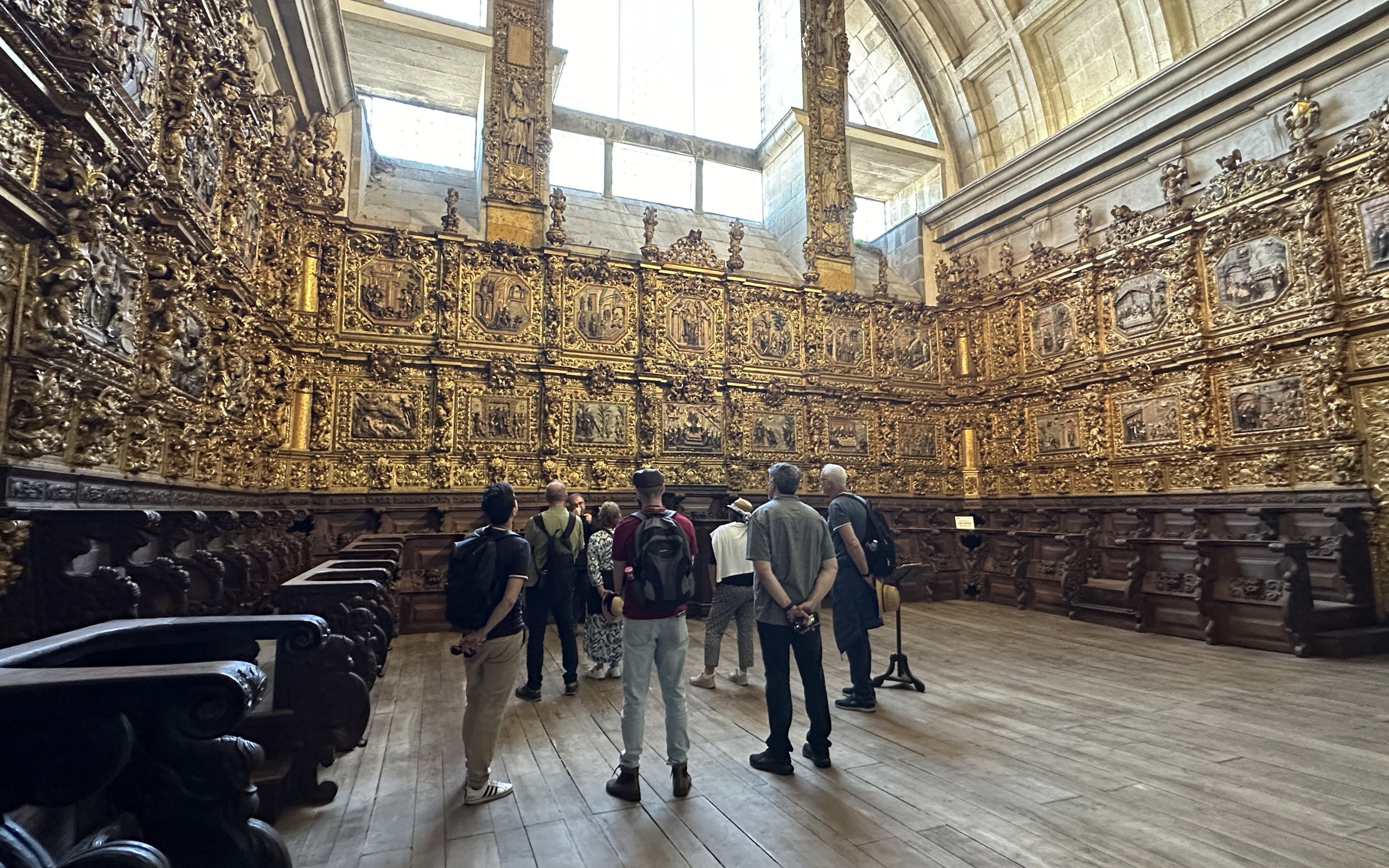 Tourists with guide inside Mosteiro de São Bento da Vitória, Porto, viewing ornate gold interior.