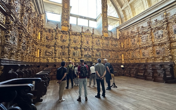 Tourists with guide inside Mosteiro de São Bento da Vitória, Porto, viewing ornate gold interior.