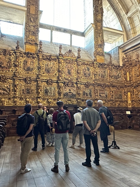 Tourists with guide inside Mosteiro de São Bento da Vitória, Porto, viewing ornate gold interior.