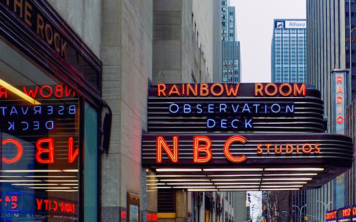 NBC Studios entrance at Rockefeller Center, New York City, featuring neon signs for Rainbow Room and Observation Deck.