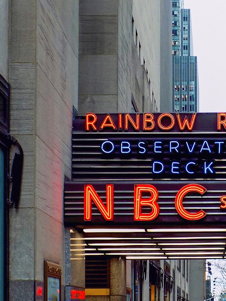 NBC Studios entrance at Rockefeller Center, New York City, featuring neon signs for Rainbow Room and Observation Deck.