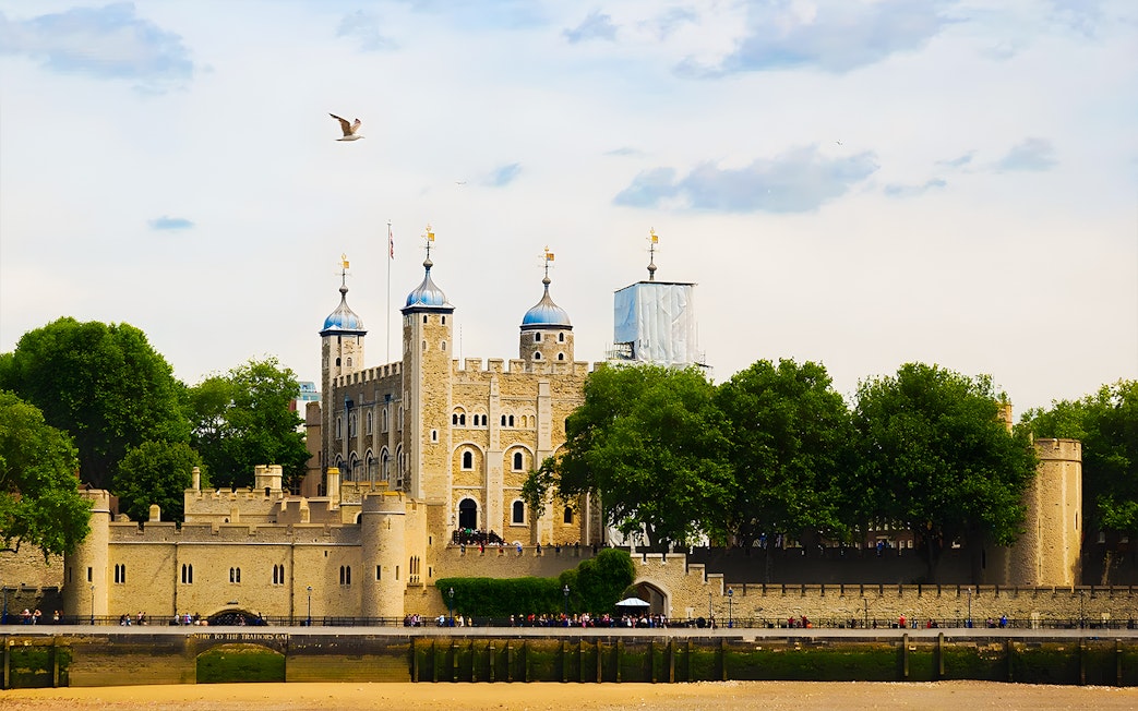 Tower of London's White Tower with surrounding trees and river view.
