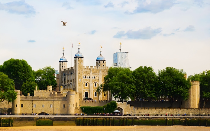 Tower of London's White Tower with surrounding trees and river view.