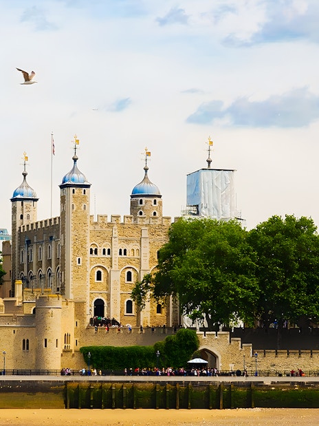 Tower of London's White Tower with surrounding trees and river view.