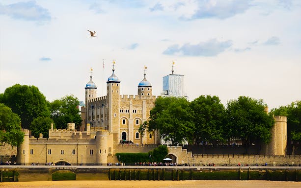 Tower of London's White Tower with surrounding trees and river view.