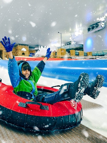 Person enjoying snow tubing at Snow Dunes Theme Park.