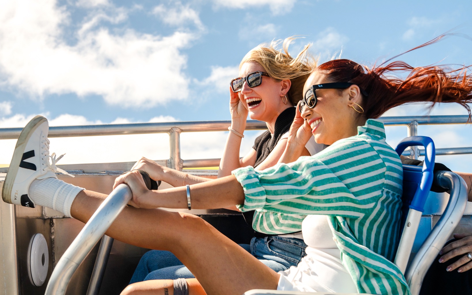 Two people enjoying a Rocketboat speedboat adventure under a clear blue sky.