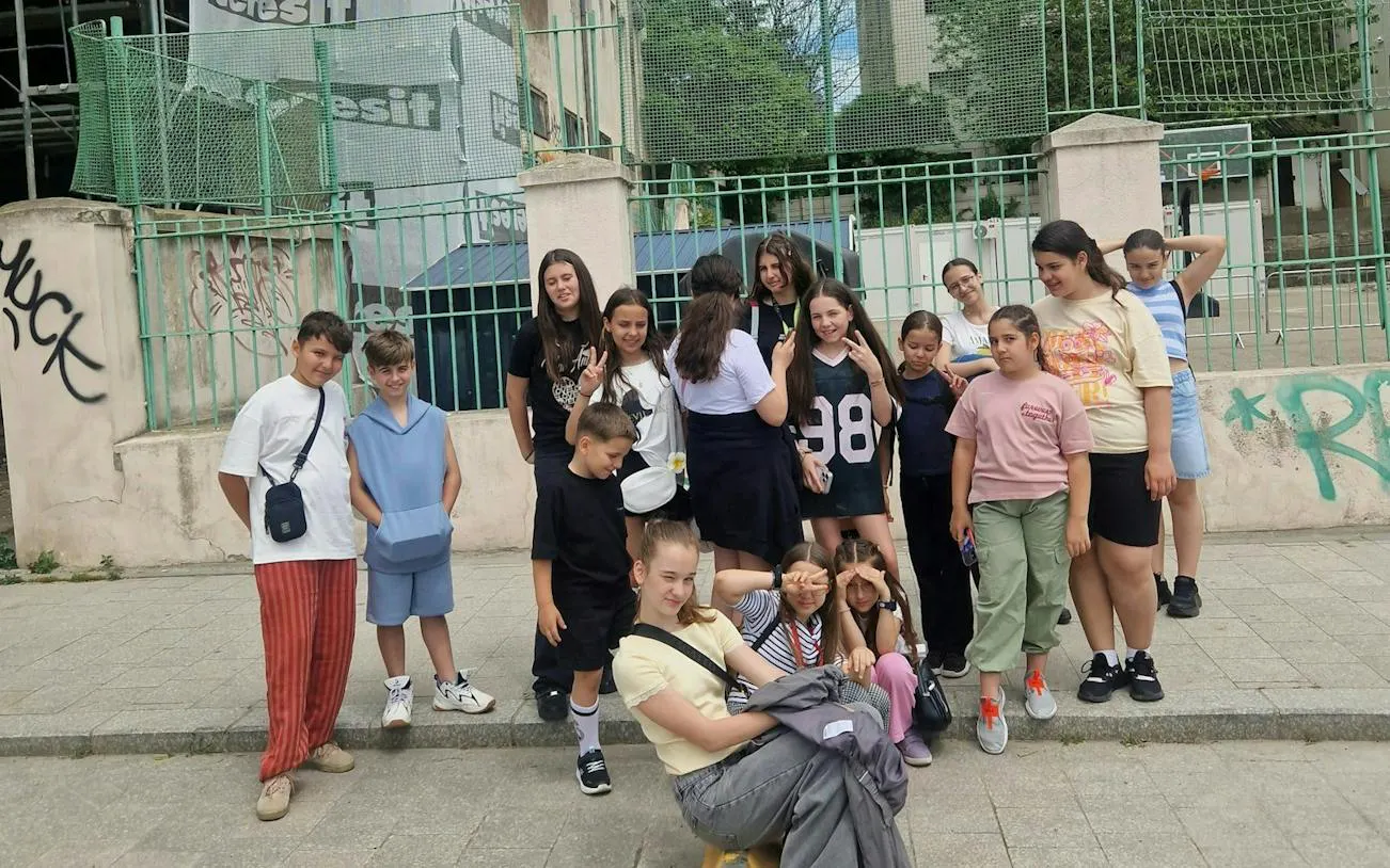 Group of children posing in front of a fenced area in Constanta for a self-guided city exploration game.