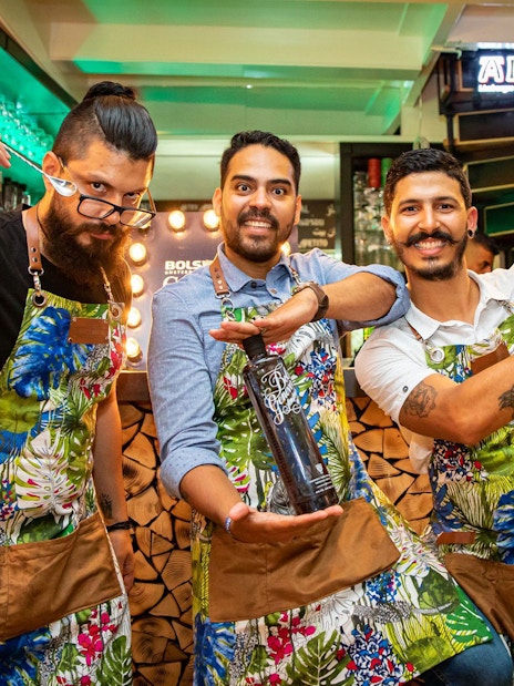 Bartenders at Amsterdam House of Bols cocktail workshop holding shakers and bottles.