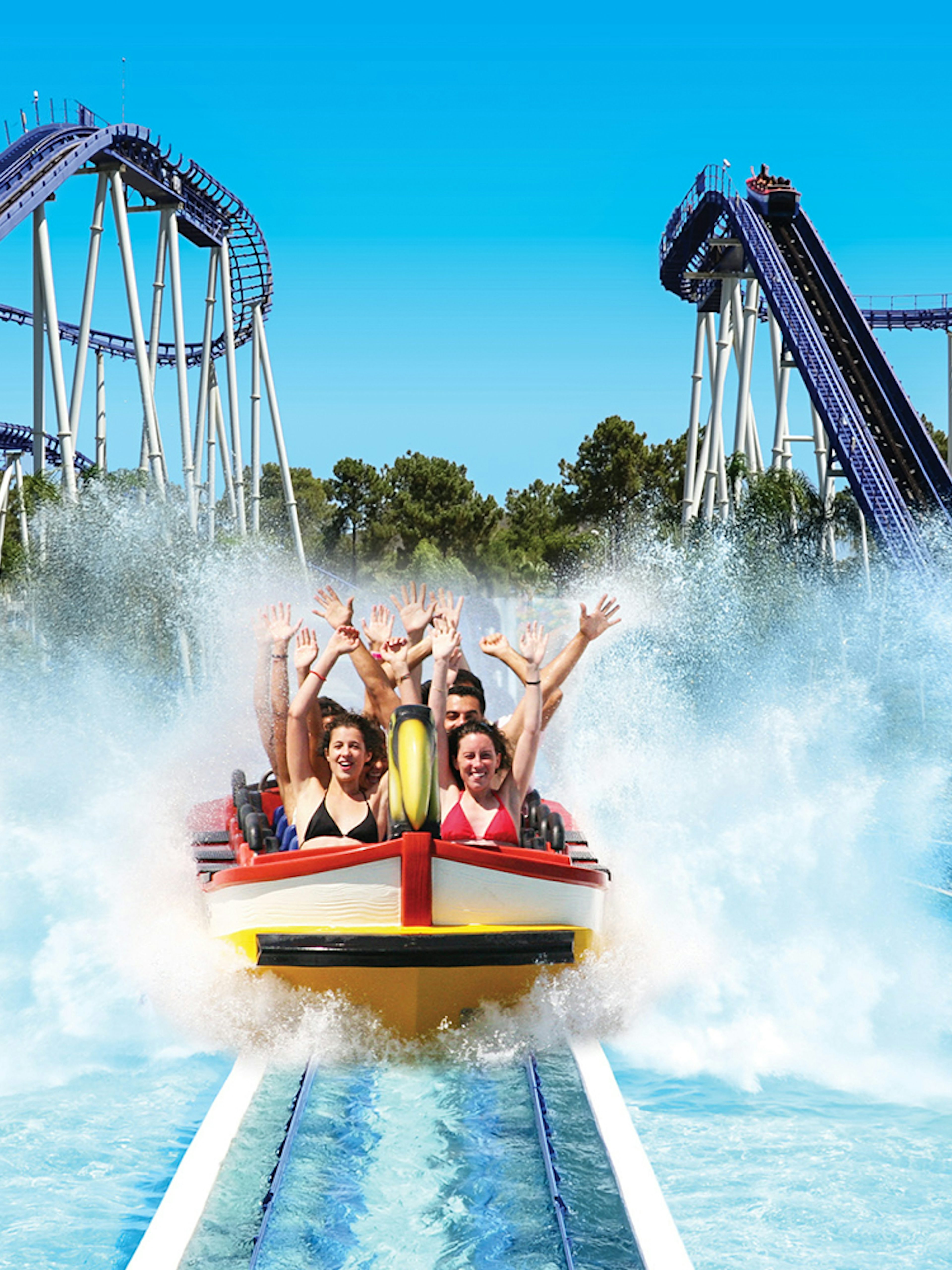 Visitors enjoying a water ride at Aquashow Water Park with roller coasters in the background.