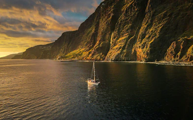 Sailboat on Madeira coast at sunset during dolphin and whale watching tour.