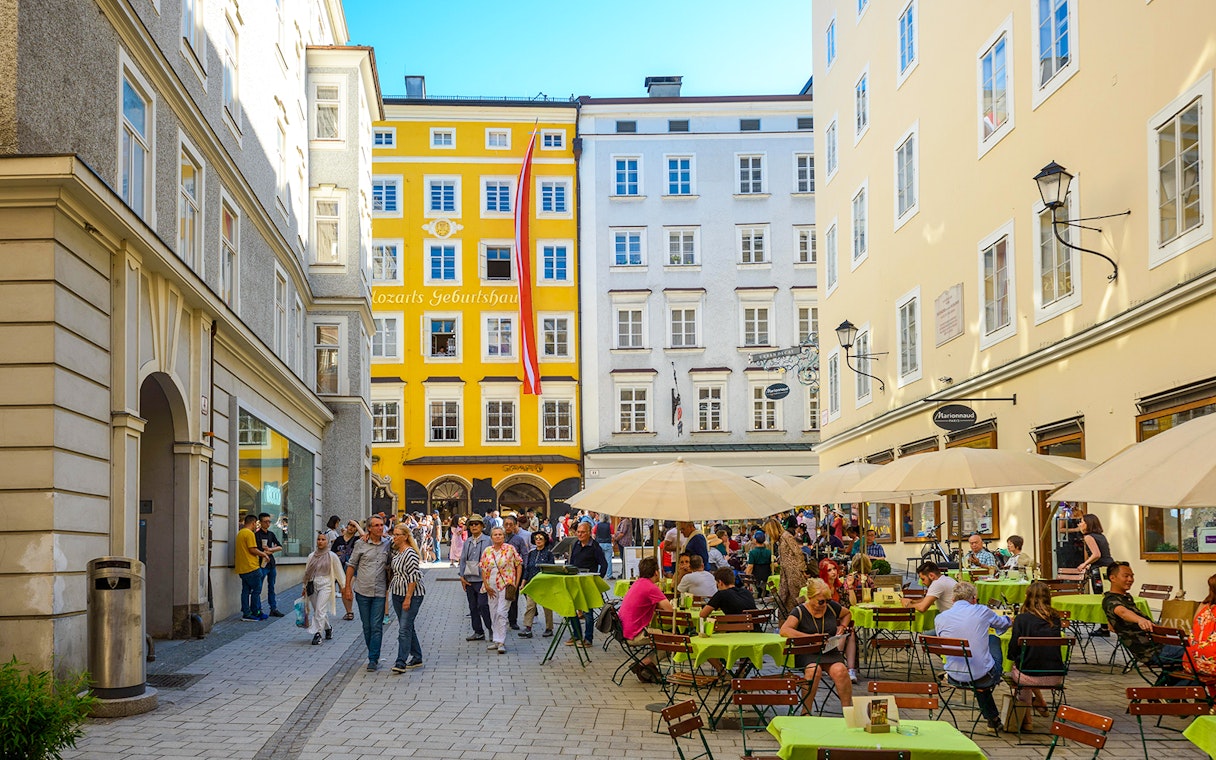 Salzburg street with outdoor cafes and Mozart's birthplace in the background.