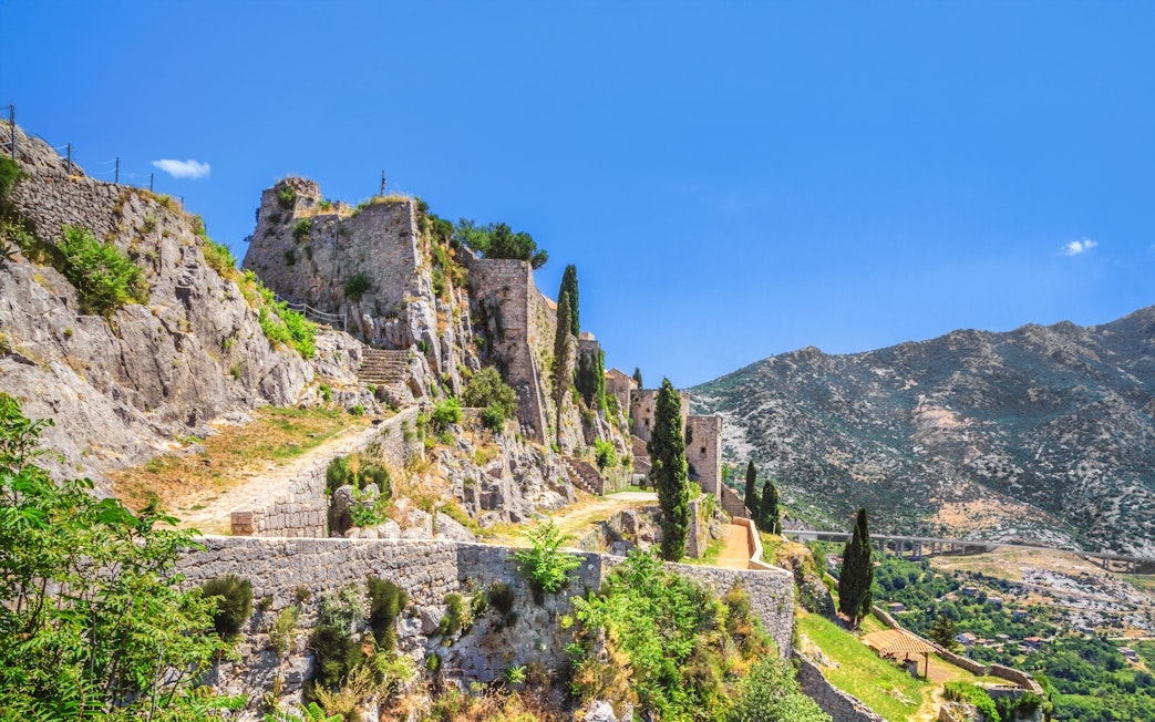 Ruins of Klis Fortress with stone walls and pathways near Split, Croatia, overlooking the Adriatic coast.