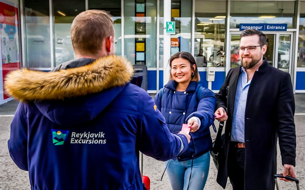 Reykjavik Excursions staff assisting travelers with tickets at Reykjavik BSI Bus Terminal.