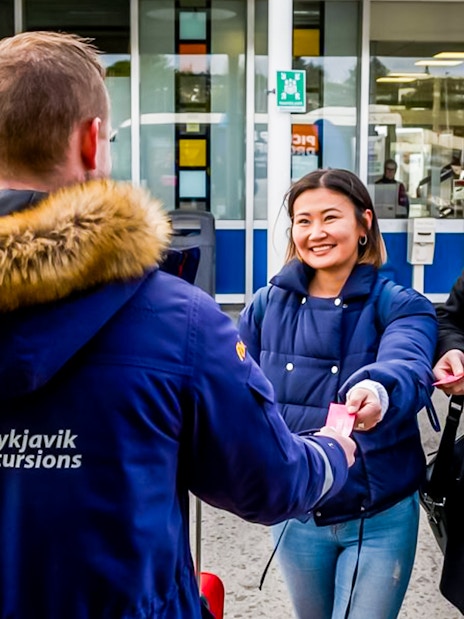Reykjavik Excursions staff assisting travelers with tickets at Reykjavik BSI Bus Terminal.