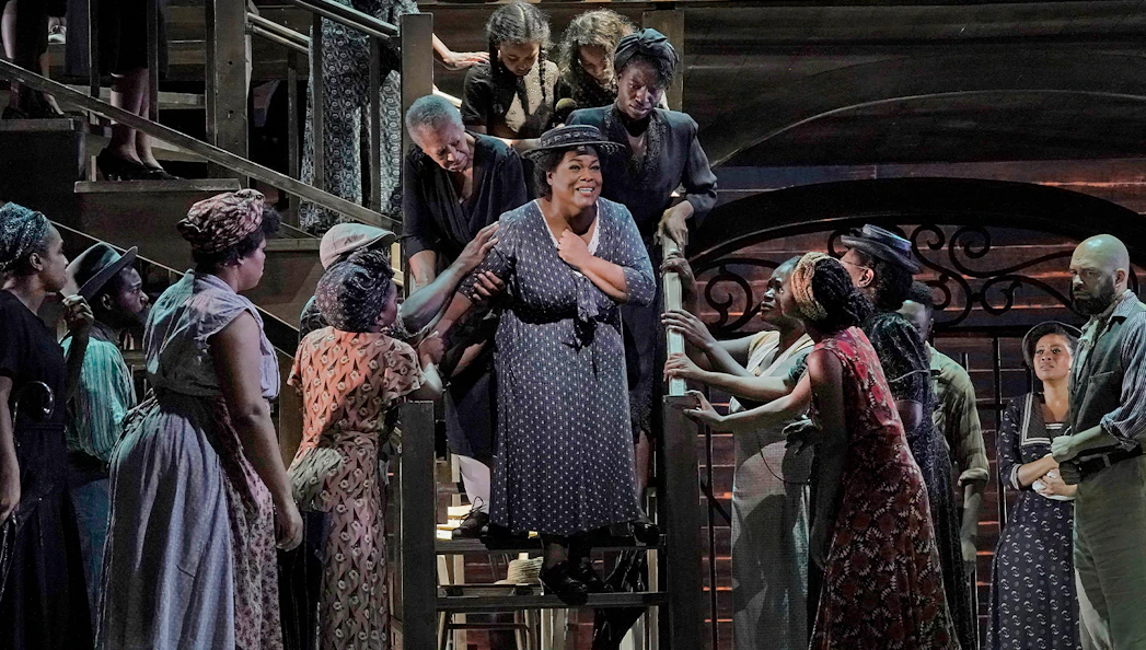 Actors performing on stage during Porgy and Bess show, surrounded by a lively ensemble.
