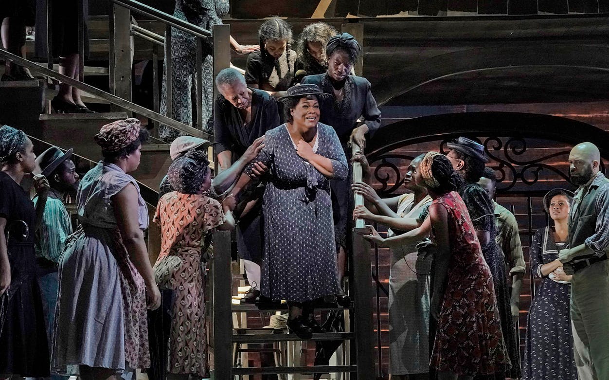 Actors performing on stage during Porgy and Bess show, surrounded by a lively ensemble.