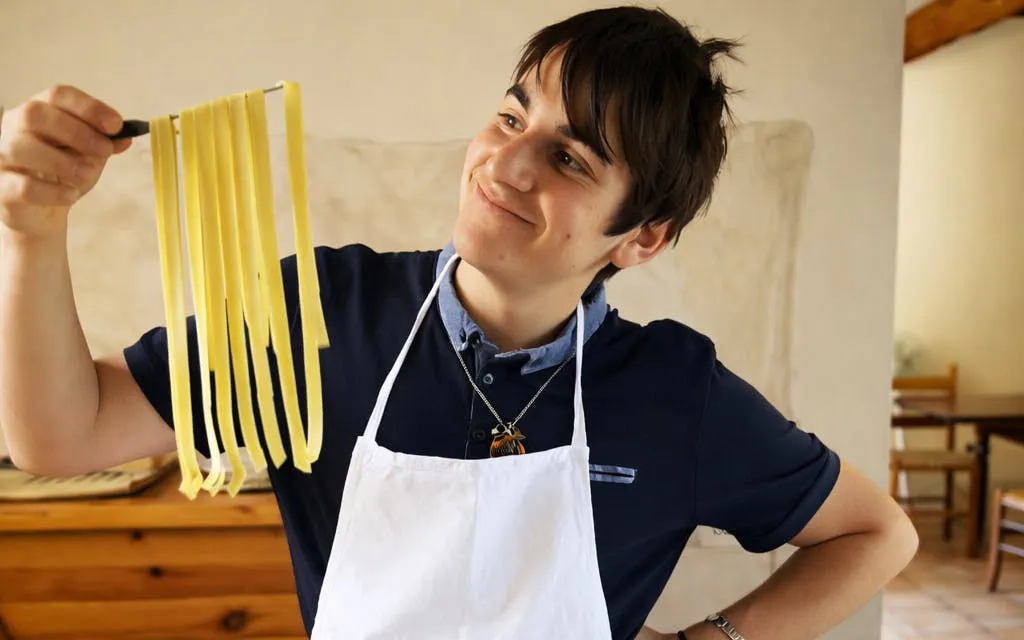 Man holding fresh pasta during a cooking class in Tuscany.